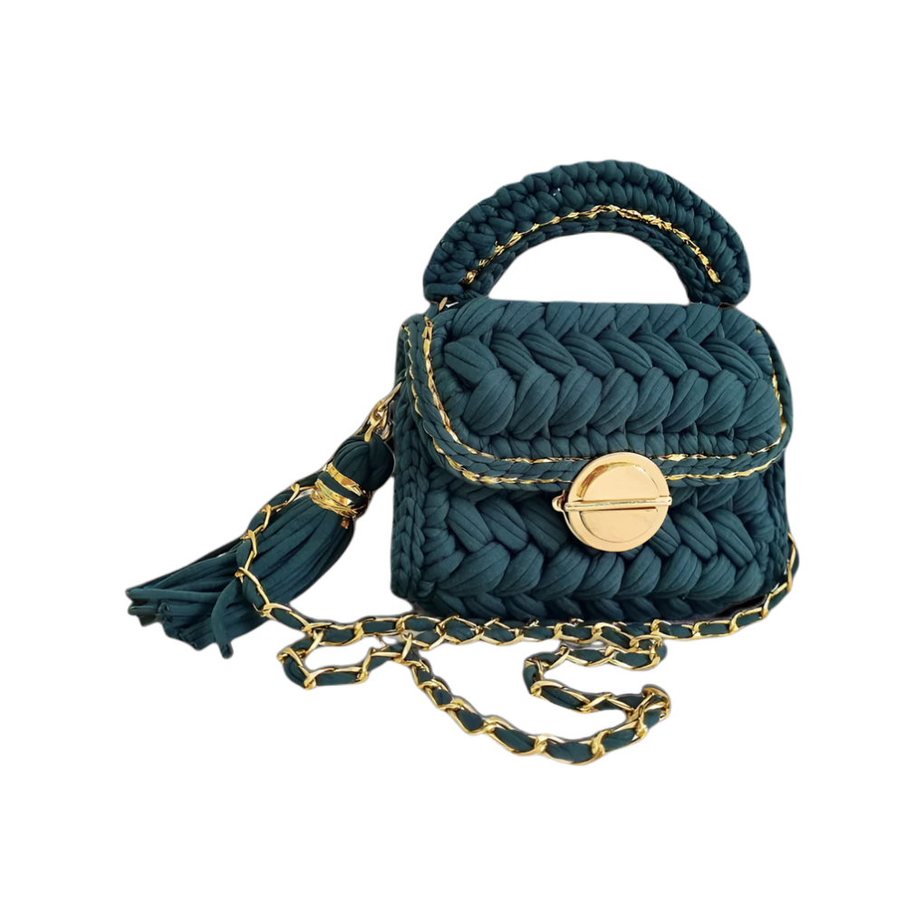 Brunch at Tiffany’s – Gleam Blue Mirage crochet handbag in deep teal with shimmering gold trim and gold clasp, styled as a crossbody on a neutral-toned outfit.